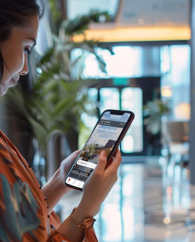 A woman holding her phones look at the Radisson Rewards mobile app homepage.