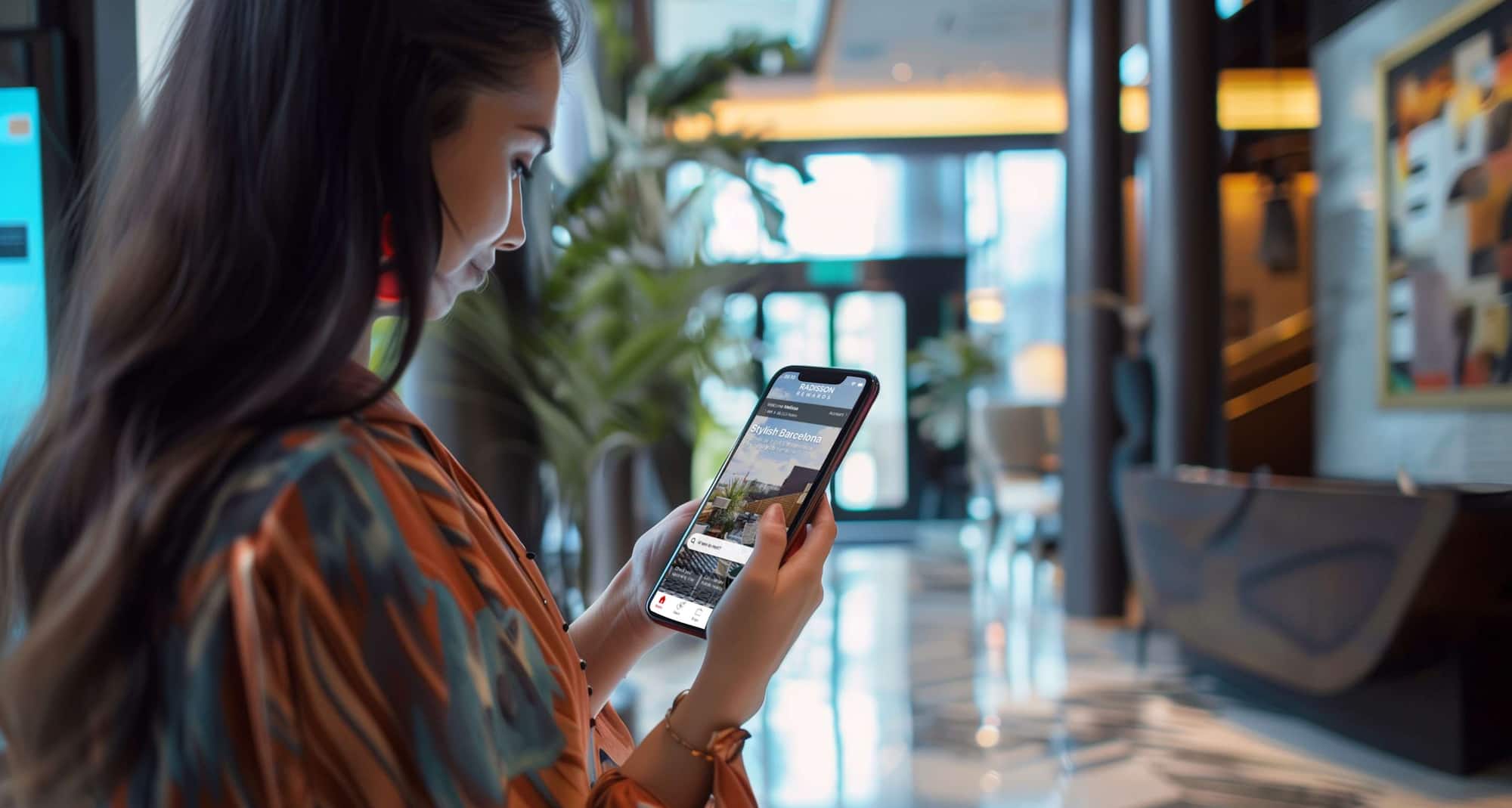 A woman holding her phones look at the Radisson Rewards mobile app homepage.