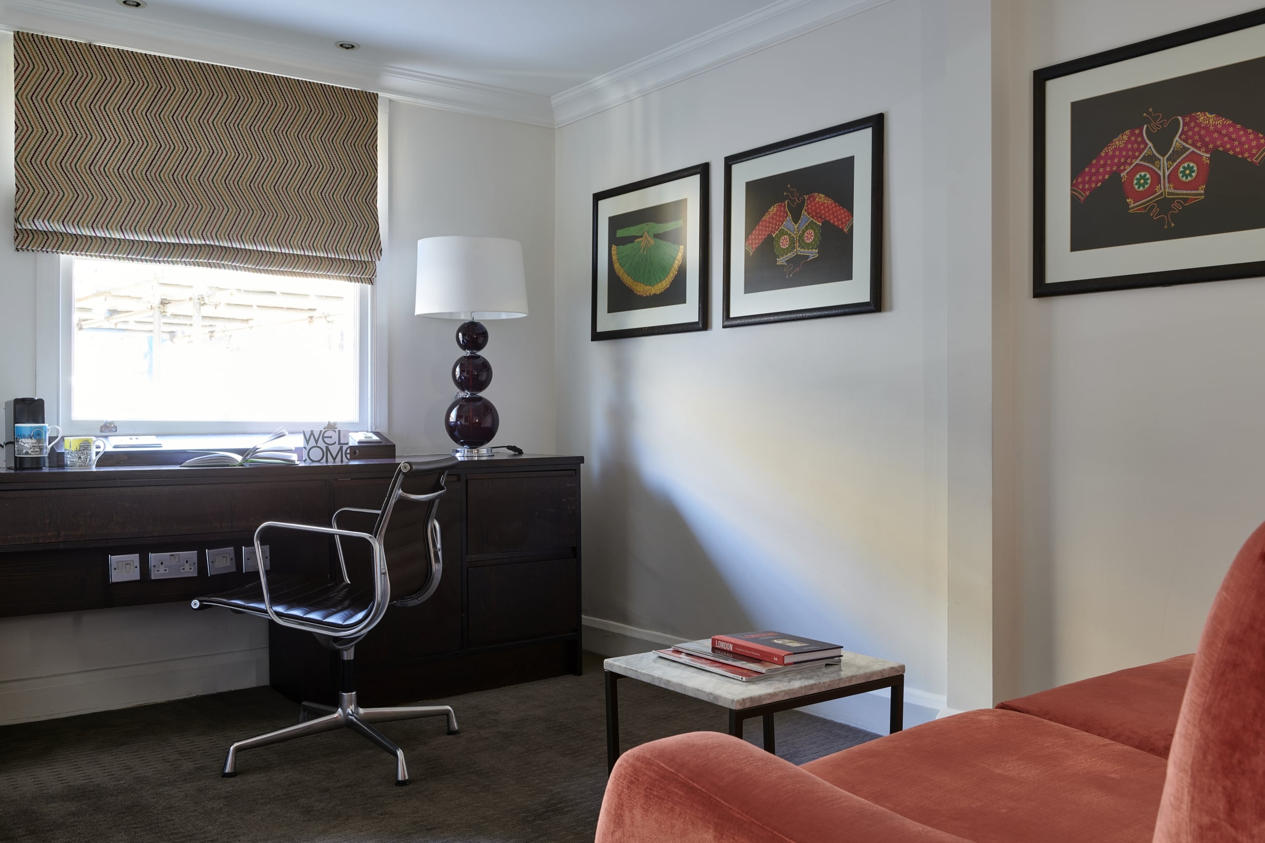 Junior Suite living room with work desk, office chair, sitting area, and framed wall art.