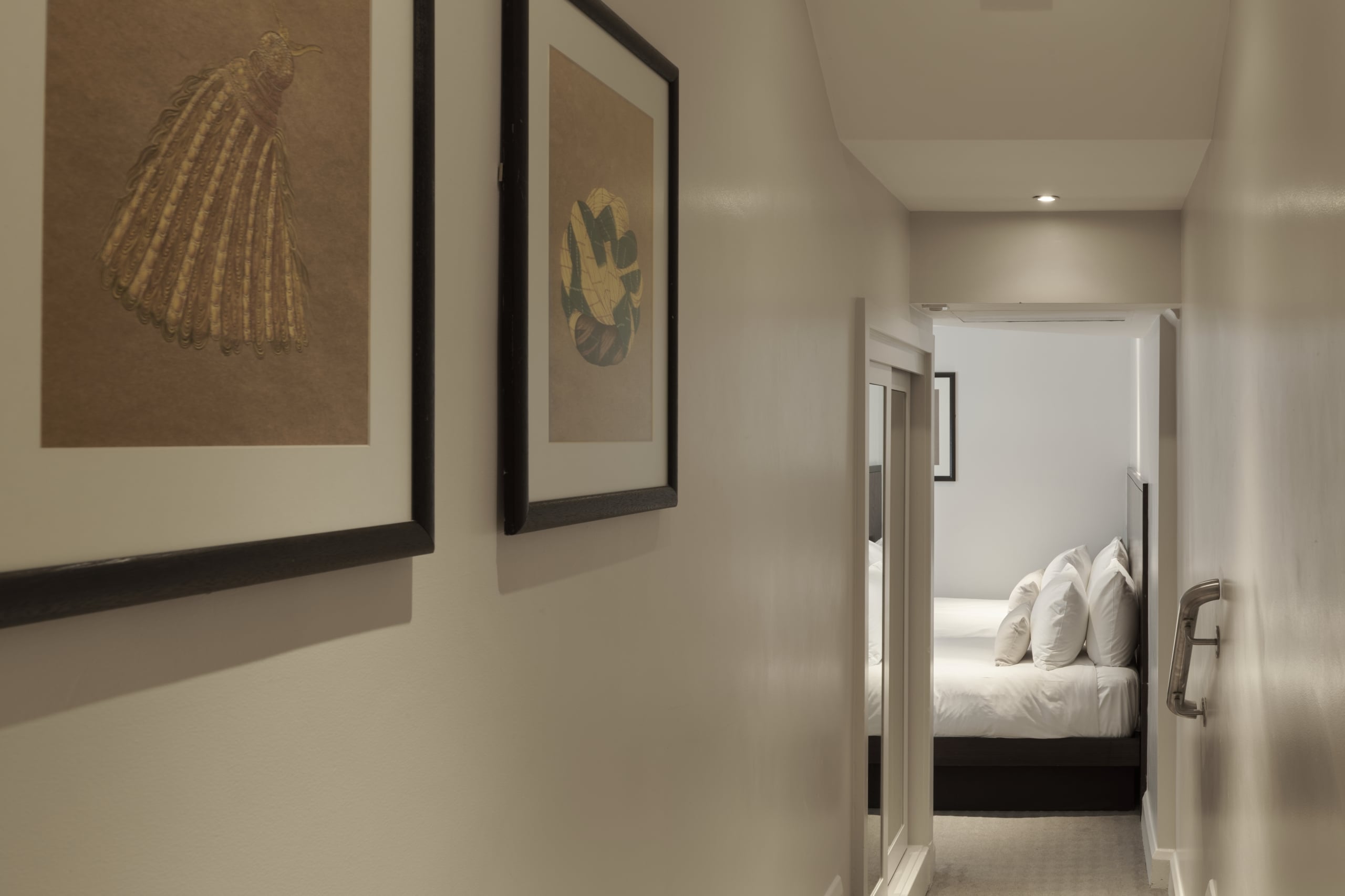 Standard twin room corridor featuring tasteful wall art hung left, with a silver handrail positioned top of the stairs, right.